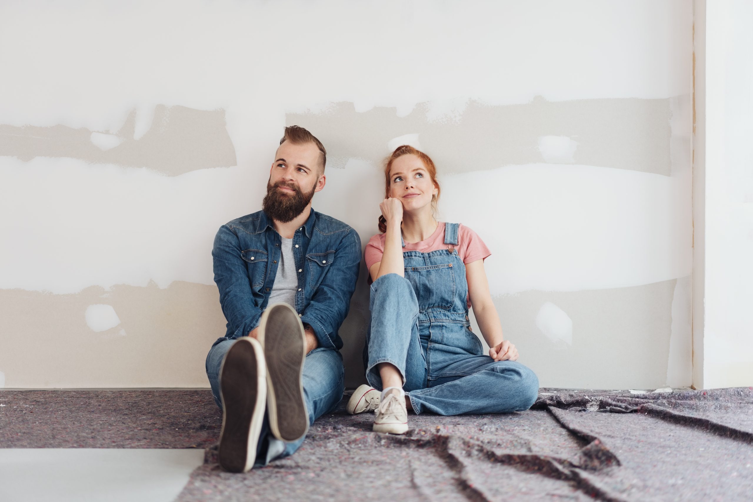 Young couple sitting on the floor side by side contemplating renovation options
